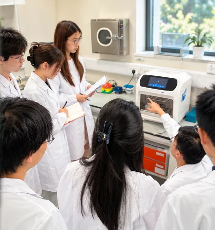 Students in lab coats at laboratory equipment